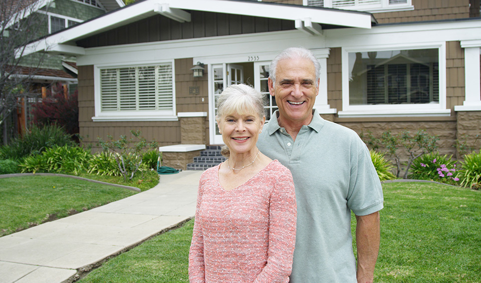 Senior couple in front of their home considering a reverse mortgage